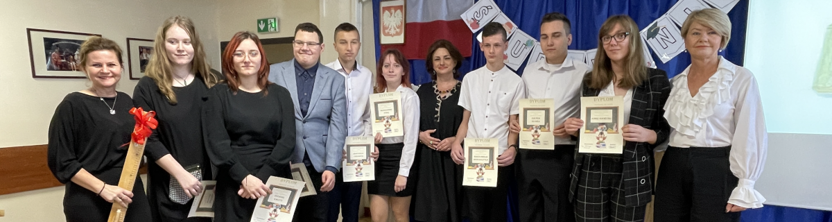 Uczniowie wraz z paniami dyrektor i wychowawczynią po ślubowaniu. Wszyscy ubrani na biało-czarno.